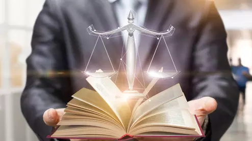 The scales of justice coming out of a book
