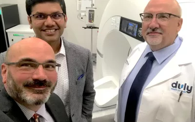 Radiology Business/Cardiovascular Business Digital Editor Dave Fornell with Sujith Kalathiveetil, MD, FACC, Duly's direc­tor of cardiac imaging, and Evans Pap­pas, MD, chair of the Duly Depart­ment of Car­di­ol­o­gy, in front of their CardioGraphe dedicated CT scanner at their Lisle, IL, clinic.